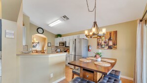 Een moderne keuken met een centraal eiland, roestvrijstalen apparatuur en een eethoek met een houten tafel en zachte banken.