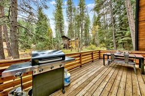A wooden deck with a barbecue grill, a table, and benches.
