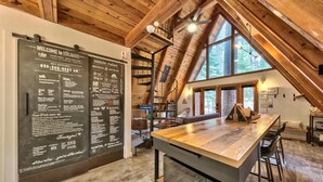 A rustic interior with a wooden ceiling, a long table, and a blackboard with information. - Külhaus Cabin - Romantic A-frame Adventure, BBQ (South Lake Tahoe)