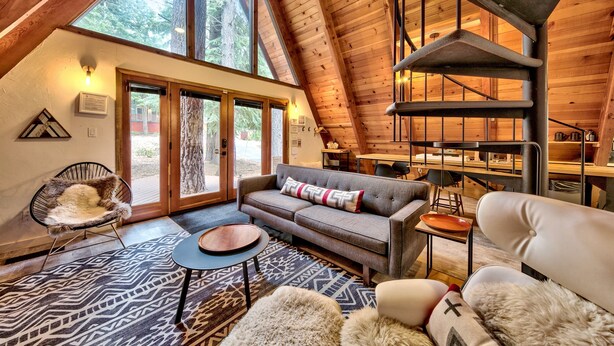 A cozy, log-floored living area with a sofa, chairs, and a fireplace. - Külhaus Cabin - Romantic A-frame Adventure, BBQ (South Lake Tahoe)