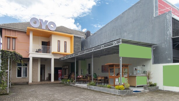 Un bâtiment sur lequel on peut lire l’inscription « OYO », et qui dispose d’un espace extérieur abrité avec des tables et des chaises.