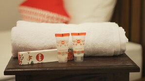 Une salle de bain bien rangée, avec une serviette blanche, deux produits de soins corporels de la marque OYO et une boîte posée sur une surface en bois.