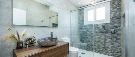 A modern bathroom with a glass-enclosed shower, a wooden vanity, and a large mirror.