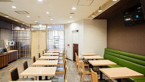 Interior moderno de restaurante com mesas e cadeiras de madeira, área de assentos em camarote verde e um balcão com cardápio.
