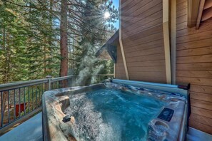 Un bain à remous sur une terrasse en bois, avec vue sur de grands arbres.