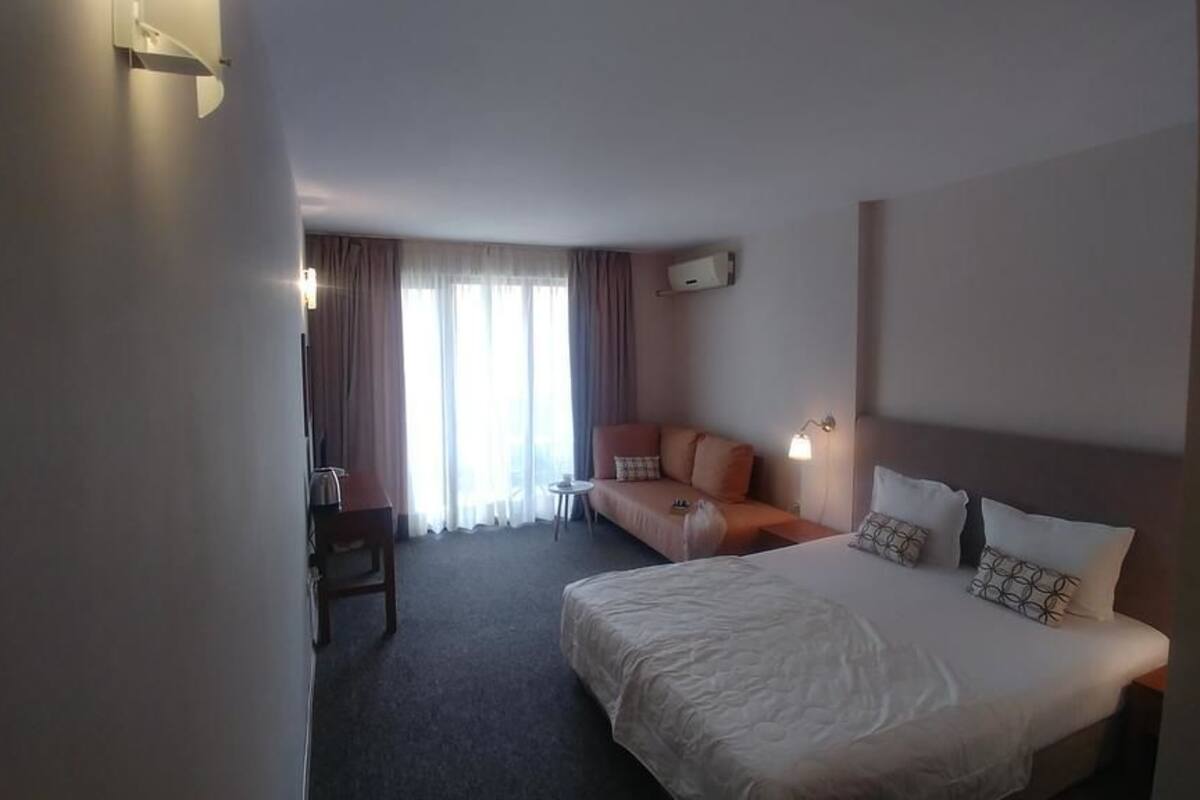 A hotel room with a bed, a sofa, a desk, and a chair.