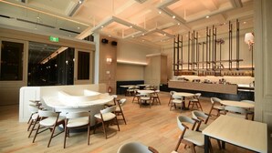 Un interior de restaurante moderno con una zona de estar central, una barra y un techo alto con iluminación empotrada.