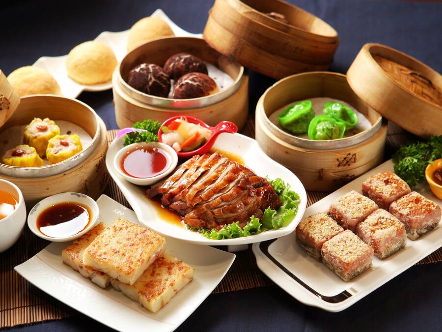 Ett urval av asiatiska rätter, inklusive dim sum, en tallrik med grillat kött och flera mindre rätter med soppa och grönsaker.