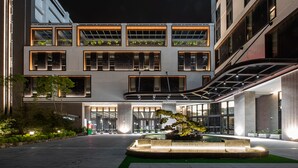 Un hotel moderno con un patio central, una galería techada y una zona de piscina.