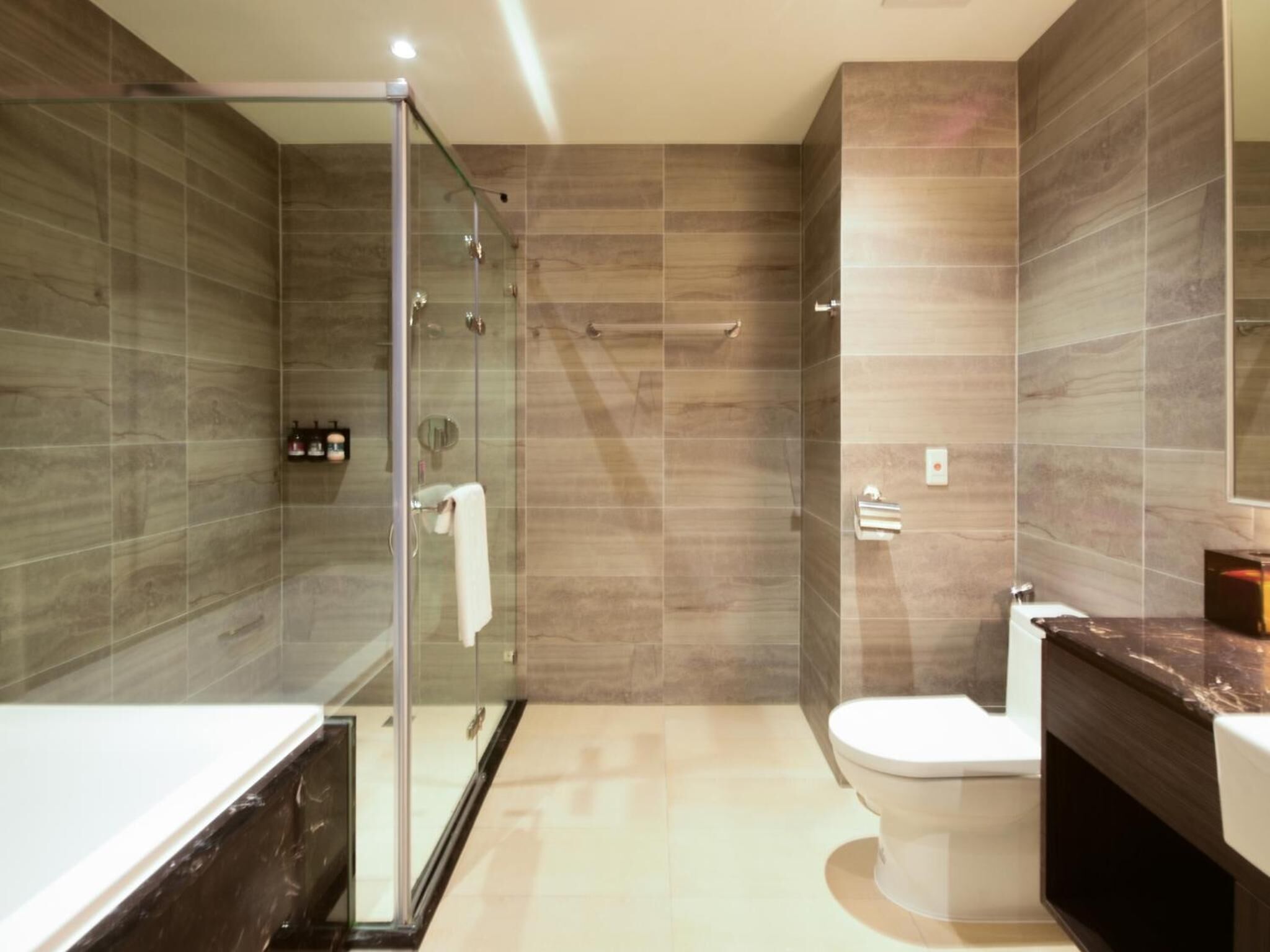 Un baño moderno con cabina de ducha de vidrio, inodoro y tocador con encimera de mármol.