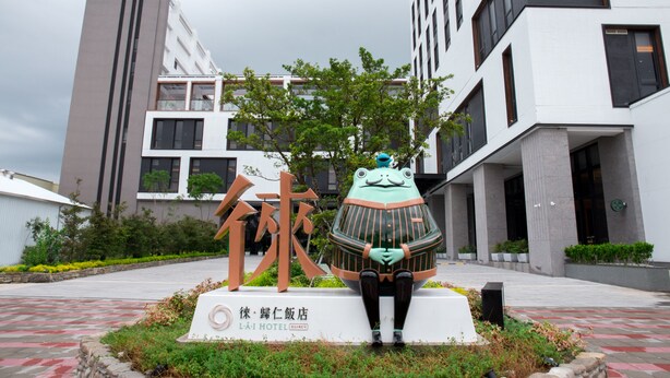 Un edificio moderno con un gran letrero que presenta una escultura de rana y caracteres chinos.