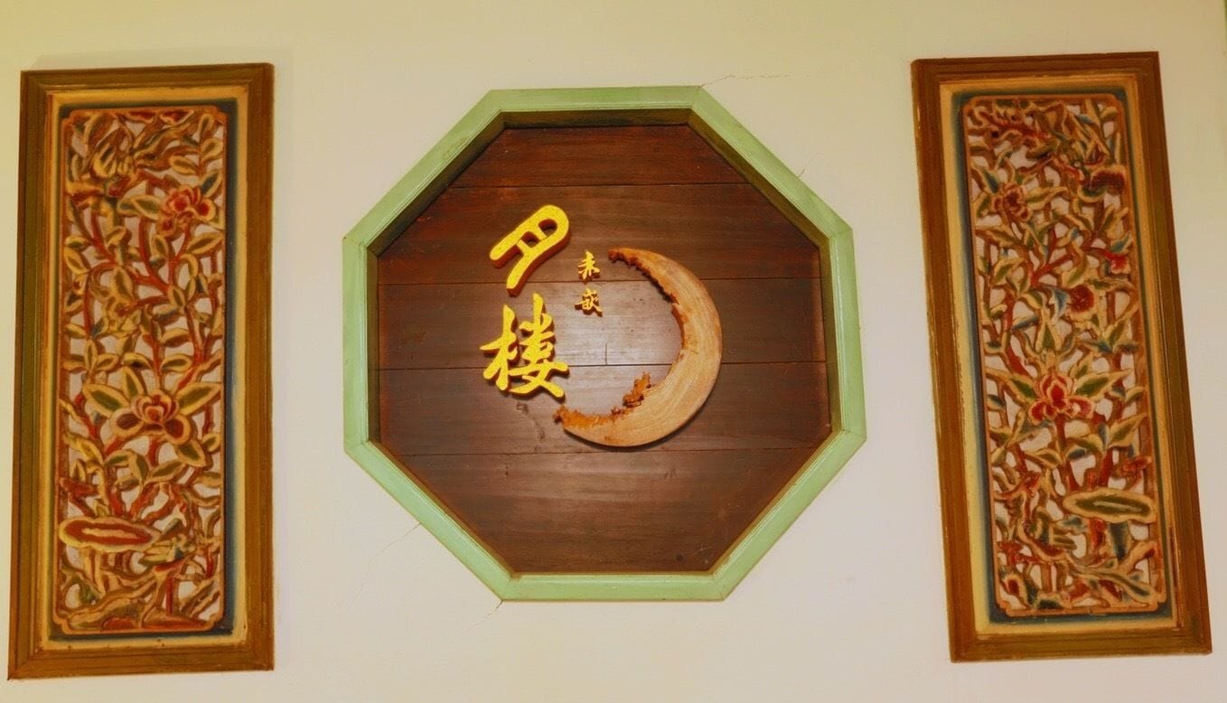 A wooden octagonal wall decoration with Chinese characters and a crescent moon, flanked by two similar framed floral designs.