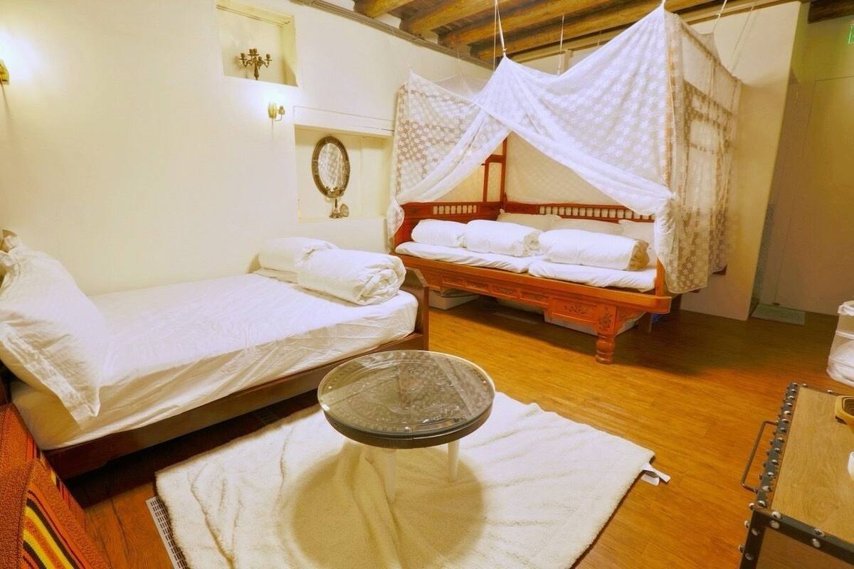 A room with two beds, a hanging chair, and a small table with a tray.