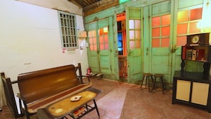 A room with a wooden bench, a small table with a plate, a cabinet with books, and a green door with windows. - Moon House Tainan (Tainan)