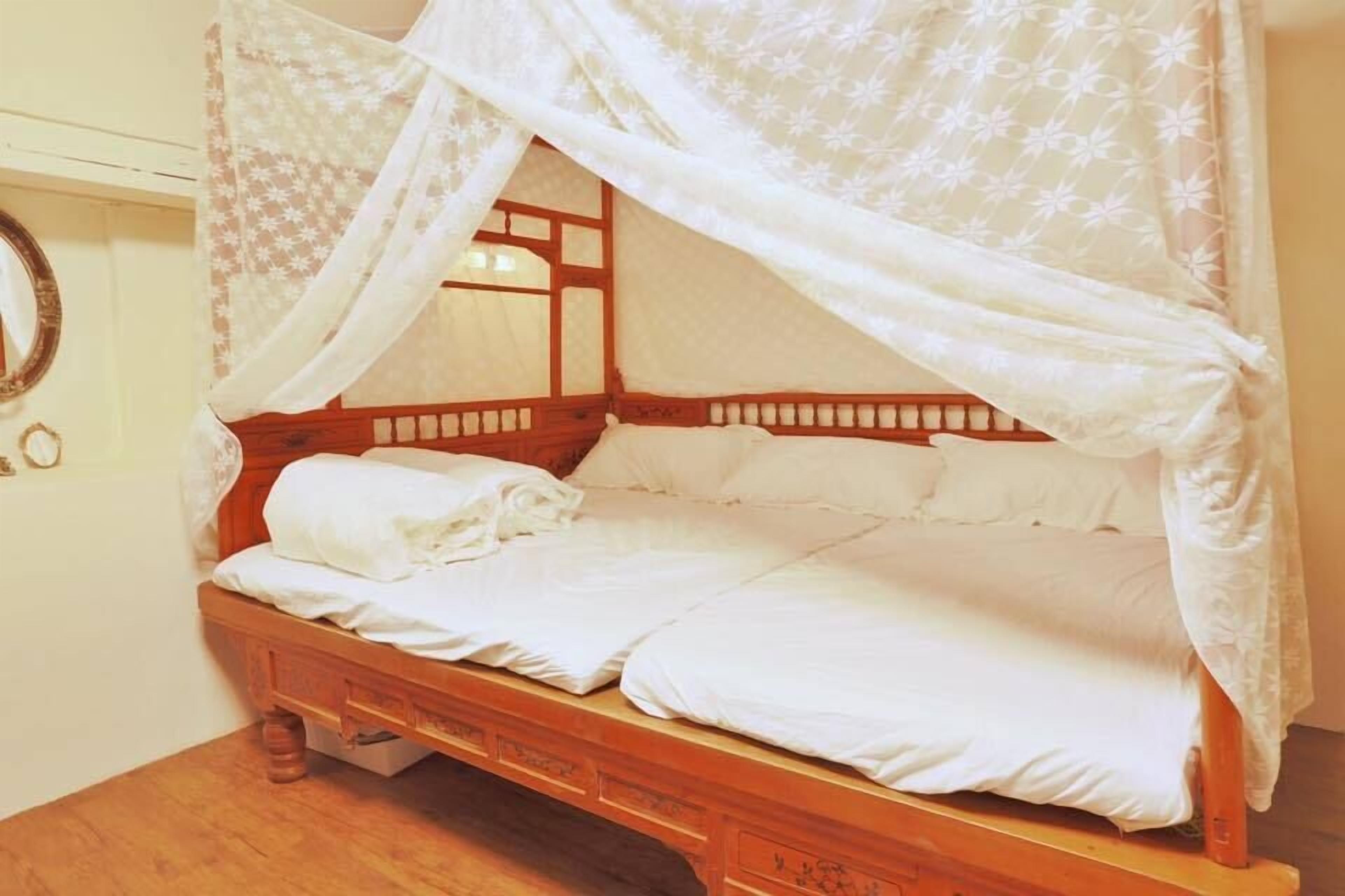 A wooden four-poster bed with white bedding and a canopy.