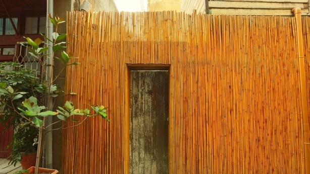Una cerca de bambú con una pequeña puerta en el centro.