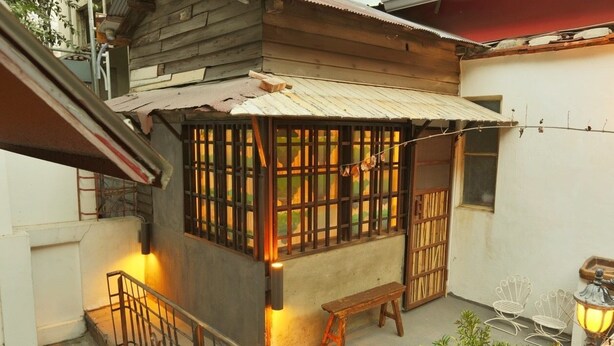 A small wooden house with a corrugated metal roof, a wooden bench, and two white metal chairs. - Moon House Tainan (Tainan)
