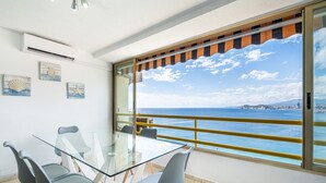 A dining area with a glass table and chairs, a view of the sea, and a balcony with a railing. - Don Miguel 1 18-A (Benidorm)