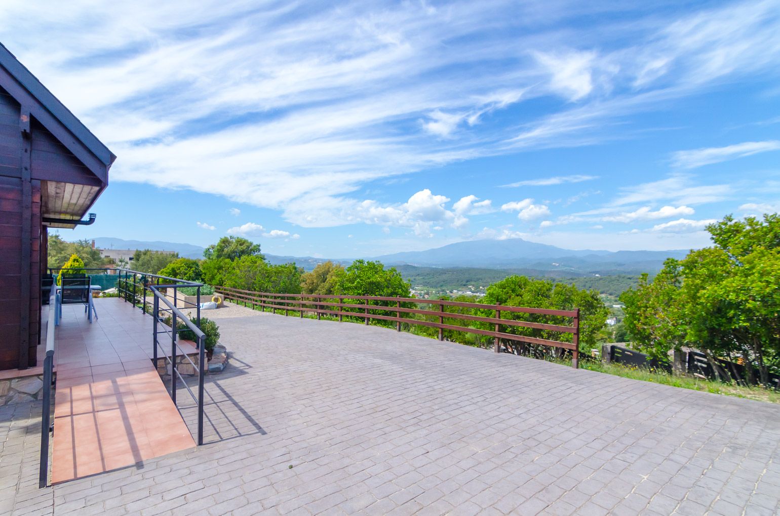 Una terraza empedrada con barandilla de madera que ofrece vistas panorámicas.