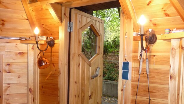 A wooden cabin with a hexagonal door, a small wooden bench, and a white fluffy rug. - Landhaus Balu - fantastic half-timbered holiday home in Oberberg (Nümbrecht)