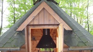 A wooden cabin with a chimney, a table, and a bench inside. - Landhaus Balu - fantastic half-timbered holiday home in Oberberg (Nümbrecht)