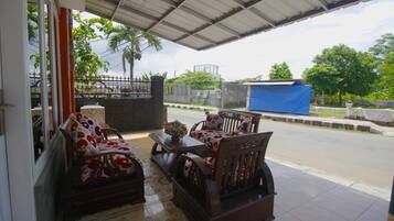 A covered outdoor seating area with wooden furniture and a tiled floor.