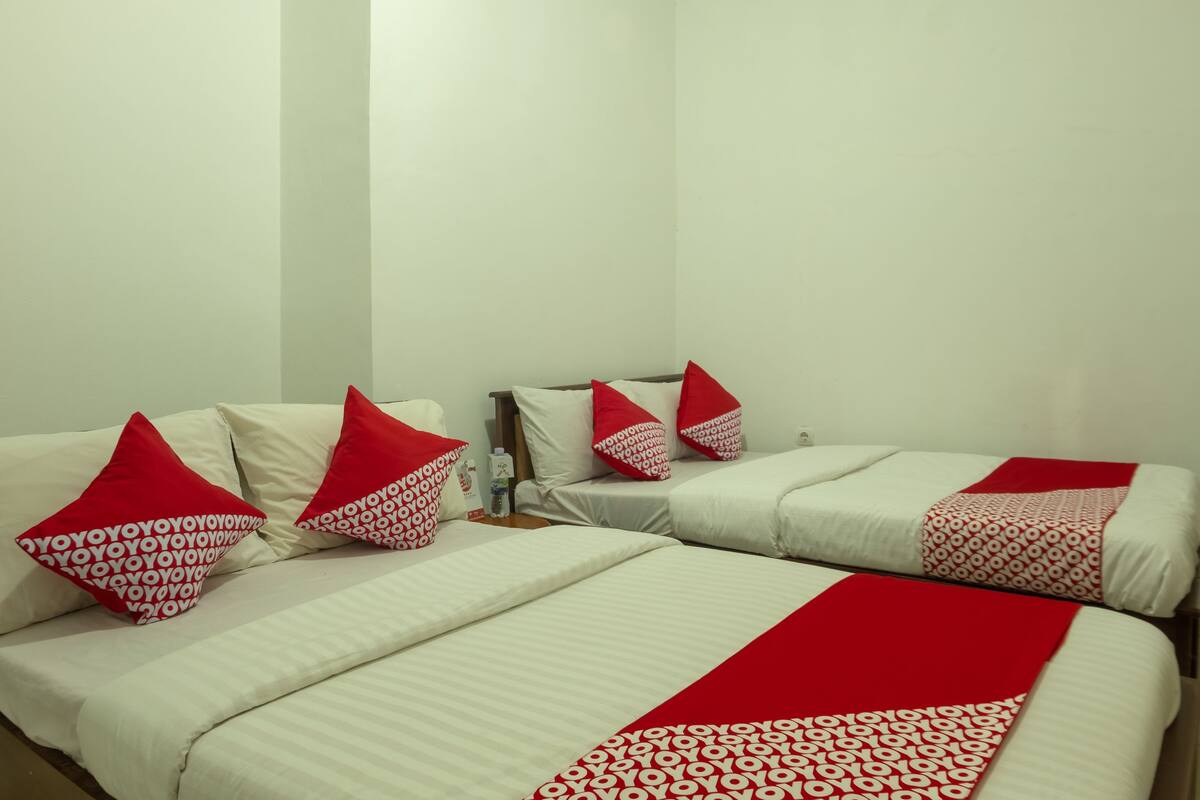 Ein Hotelzimmer mit zwei Betten, jeweils mit weißer Bettwäsche und roten Kissen.