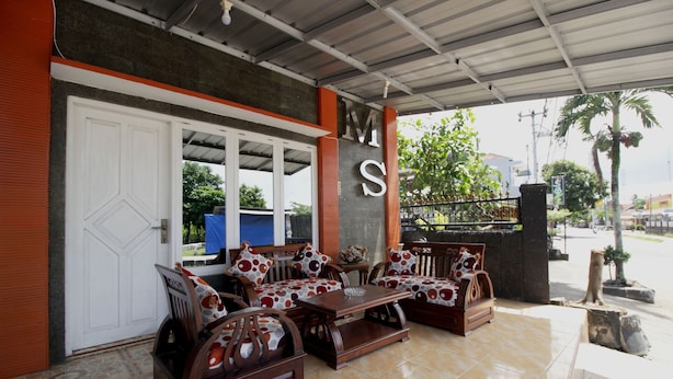 Un área de estar al aire libre con muebles de madera y piso de baldosas.