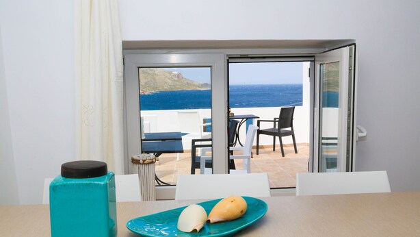 Ein Zimmer mit Tisch, Teller mit Essen und Blick auf das Meer.