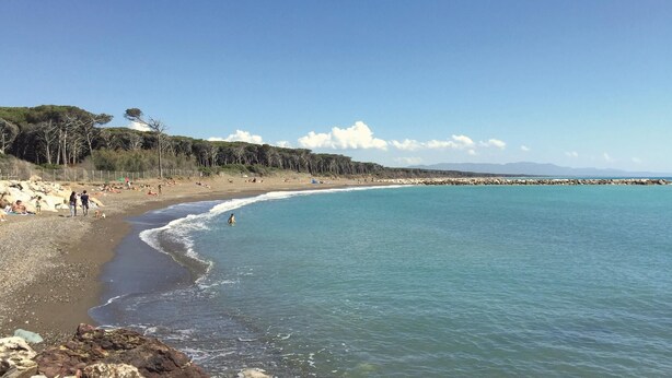 A beach with clear blue water, rocky shoreline, and people sunbathing. - Lovely home in Sassetta with swimming pool (Sassetta)