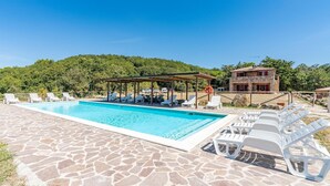 A swimming pool with lounge chairs and a covered seating area, surrounded by stone flooring and a stone building. - Lovely home in Sassetta with swimming pool (Sassetta)