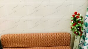 Un canapé orné d’un motif géométrique, dans une pièce dont le sol est recouvert de marbre et où l’on trouve un rideau à motifs floraux.