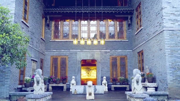 A traditional courtyard with stone lion statues, wooden doors, and hanging lanterns. - Songtsam Linka Lijiang (Lijiang)
