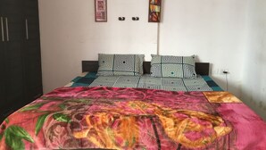 A bed with patterned bedding and a floral throw blanket. - HomeNow - Full Kadambari - Botanical Garden Metro (Noida-)