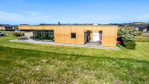 Ein modernes Gebäude mit Holzfassade, großen Glasfenstern und einem kleinen Eingang.