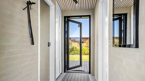 Ein moderner Flur mit einer Schiebetür, die auf einen Balkon mit Blick auf einen Garten und ein Gebäude führt.