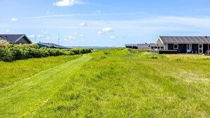 Ein grasbewachsener Pfad führt zu einer Reihe moderner Häuser mit Solaranlagen, umgeben von viel Grün.