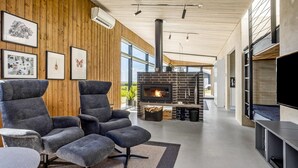 Ein modernes Wohnzimmer mit einem großen Kamin, Holzwandverkleidung und einer gemütlichen Sitzecke.
