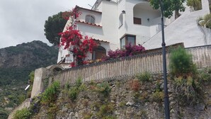 Un bâtiment blanc doté de balcons, d’un mur en pierre et d’un lampadaire.