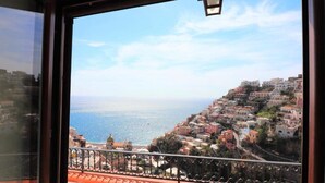 Une vue sur la côte, prise depuis un balcon doté d’une balustrade, donnant sur une ville aux bâtiments aux couleurs vives et sur la mer.