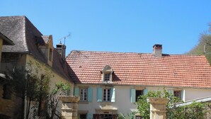 A traditional building with a red-tiled roof, a stone entrance gate, and a sign indicating it is a hotel. - Gite 8p, 3*, air-conditioned heated pool, Spa, playground, wifi, ok dog cat (MONTIGNAC-LASCAUX)