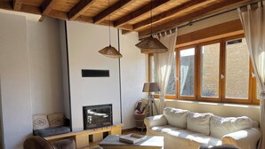 A cozy living room with a fireplace, wooden beams, a sofa, and a coffee table. - Gite 8p, 3*, air-conditioned heated pool, Spa, playground, wifi, ok dog cat (MONTIGNAC-LASCAUX)
