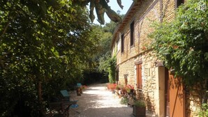 A stone building with a gravel path, wooden chairs, and potted plants. - Gite 8p, 3*, air-conditioned heated pool, Spa, playground, wifi, ok dog cat (MONTIGNAC-LASCAUX)