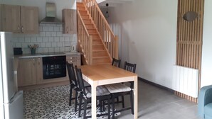 Una cocina compacta con armarios de madera, una mesa de comedor con sillas y una escalera.