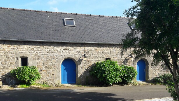 Un edificio de piedra con tres portales arqueados, cada uno con una puerta azul, y un pequeño ventanal sobre la puerta central.