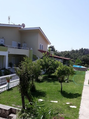 A two-story building with a balcony, a swimming pool, and a well-maintained lawn.