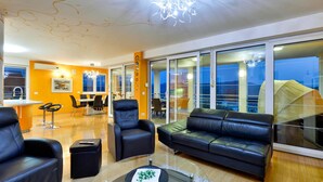 A modern living room with a glass coffee table, leather sofas, and a dining area with a view.