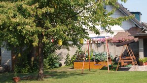 Un cortile residenziale con prato, altalene e una casetta di legno.
