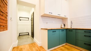 A kitchen with teal cabinets, a wooden countertop, and a tiled backsplash. - MB2- Gwarna 11 (Wroclaw)