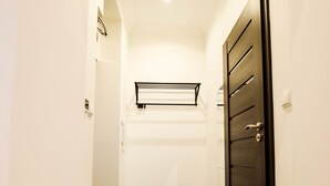 A narrow hallway with a dark wooden door, white walls, and a tiled floor. - MB2- Gwarna 11 (Wroclaw)